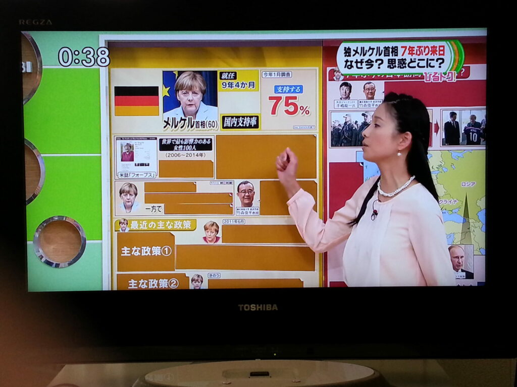 Japanisches Mittagsfernsehen: Angela Merkel wird vor schwarz-rot-goldenem Hintergrund erklärt © Sonja Blaschke